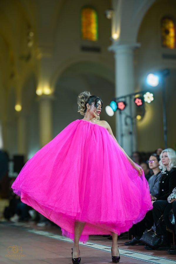 Model in a dramatic pink gown on the runway