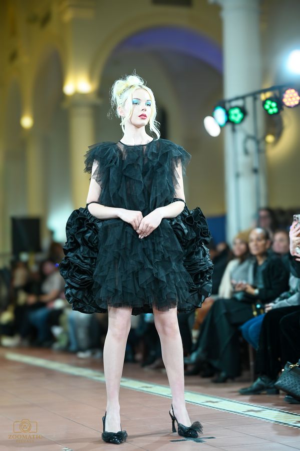 Model in a black feathered dress under stage light