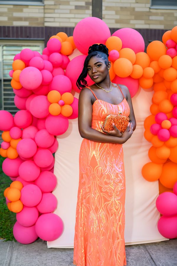 Guest in an orange gown beside a balloon installation
