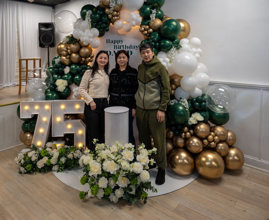 75th birthday celebration with green and gold balloon arch