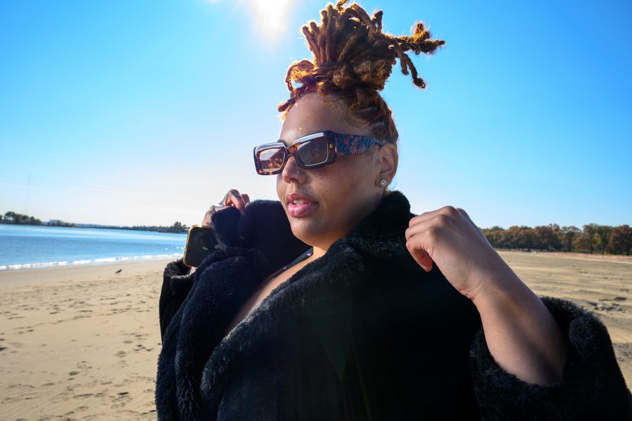 Editorial winter beach portrait in a fur coat and sunglasses